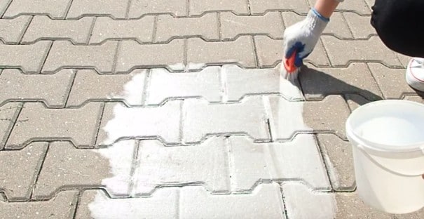 Przygotowanie podłoża przed malowaniem symbolu z szablony na kostce brukowej